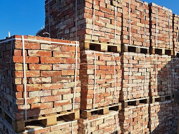 Gestapelte alte Backsteine und historische Ziegel auf Paletten für Sanierung und Denkmalpflege