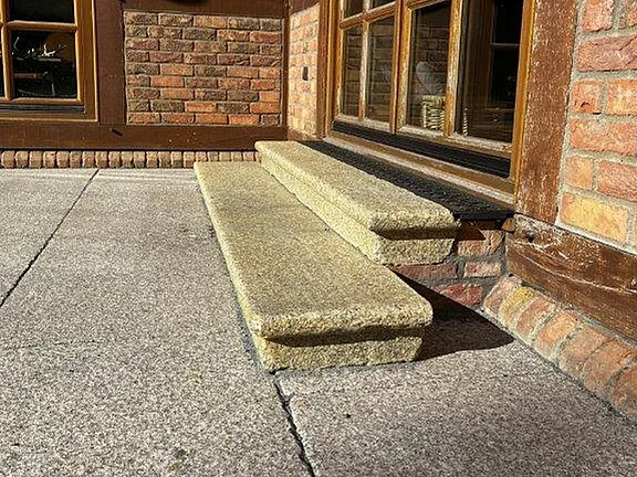 Granitplatten mit Granitstufen am Hauseingang eines Ziegelhauses