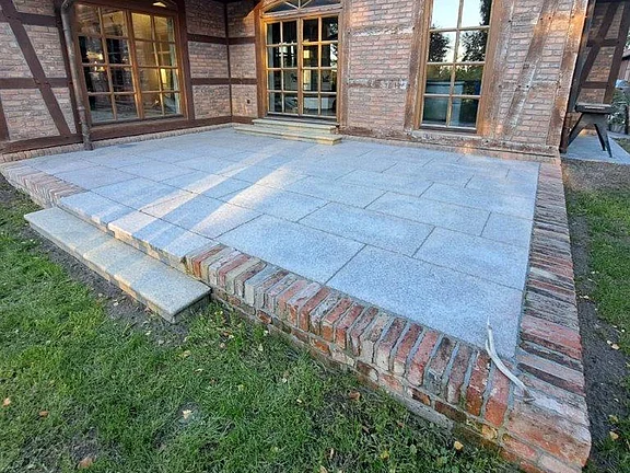 Terrasse mit Granitplatten und Einfassung aus historischen Ziegeln