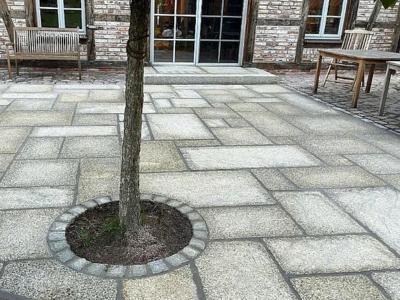 Innenhof mit alten Granitplatten und runder Baumscheibe